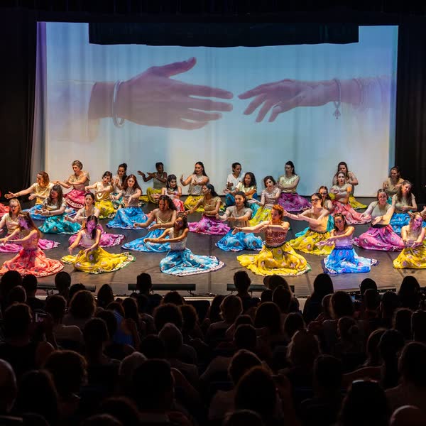 Toute la troupe assise sur scène devant une salle comble